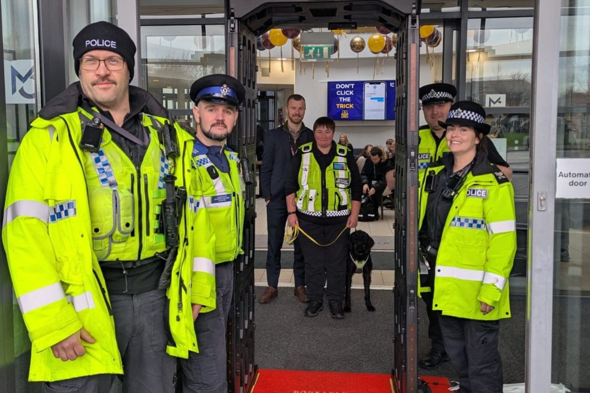 A staff member standing with the police in front of Macclesfield College's main building.