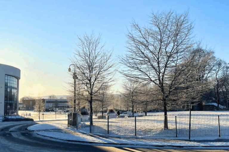 The image shows Macclesfield College in the snow on a bright day.