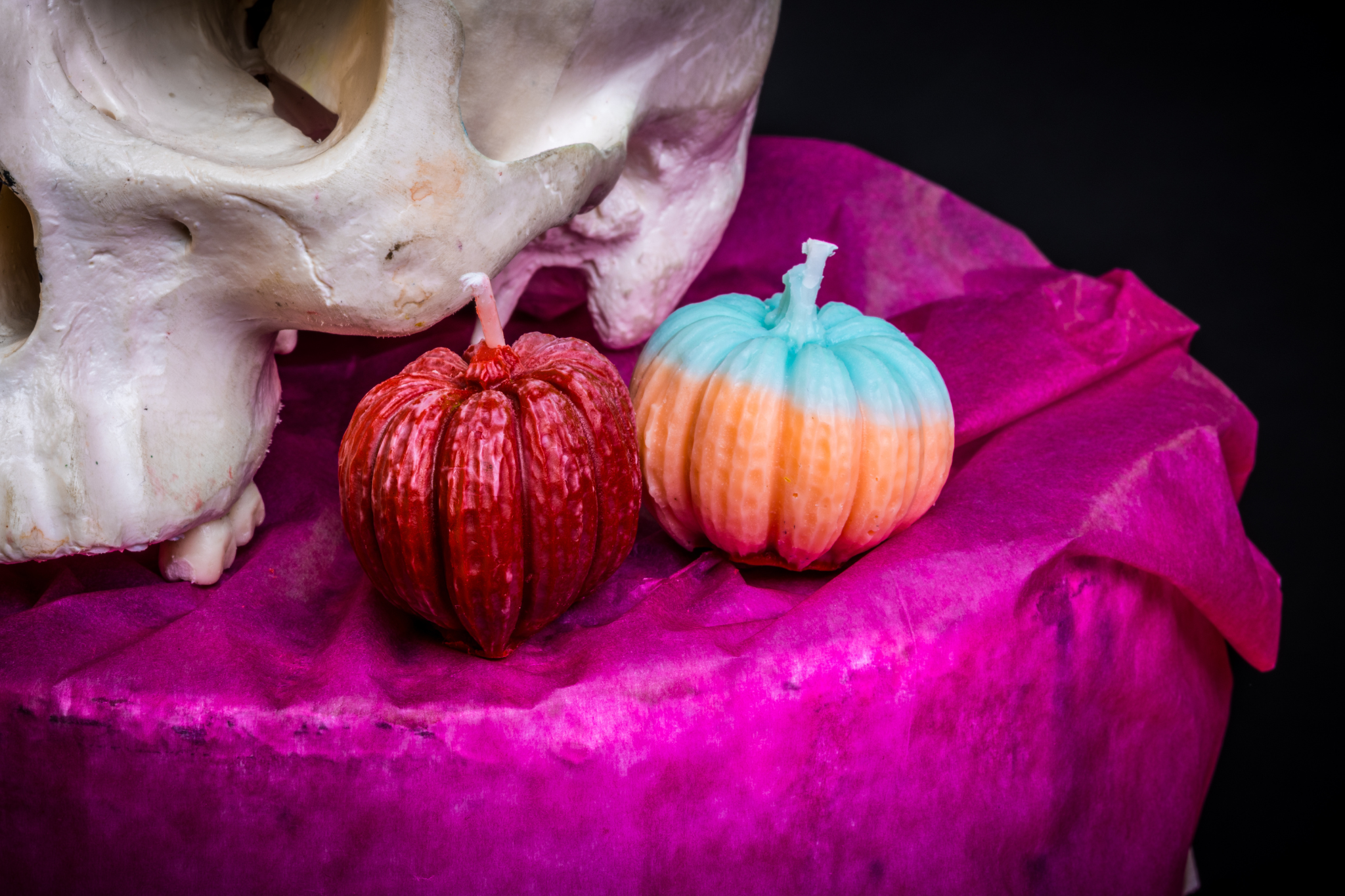 Two small pumpkin candles are placed next to a skull ornament