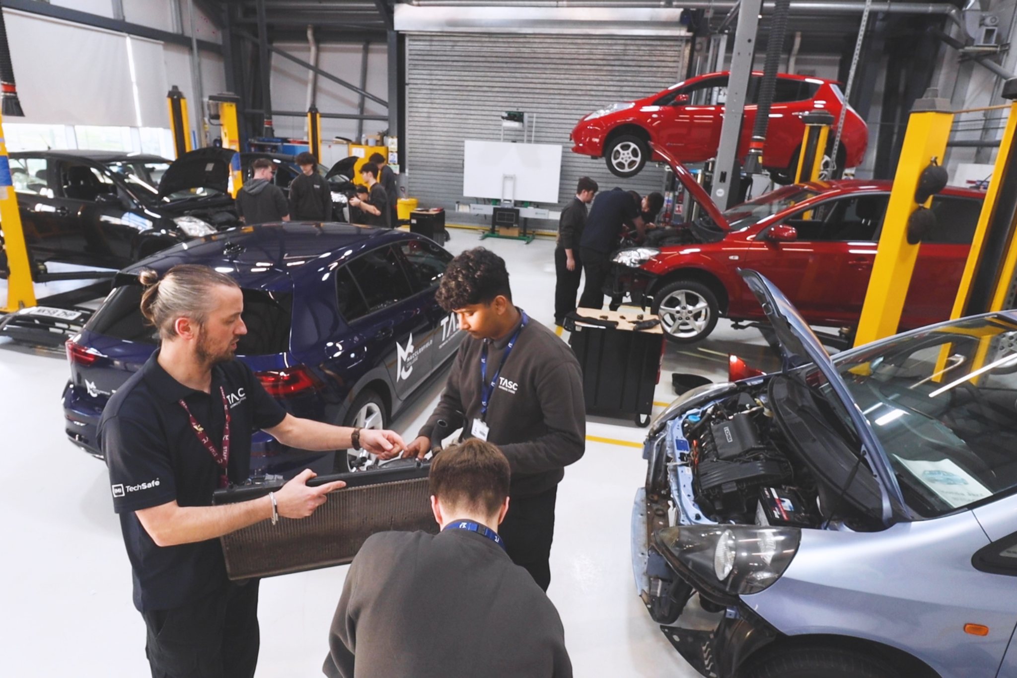 Two Automotive students and their teacher looking at car radiator fan assembly