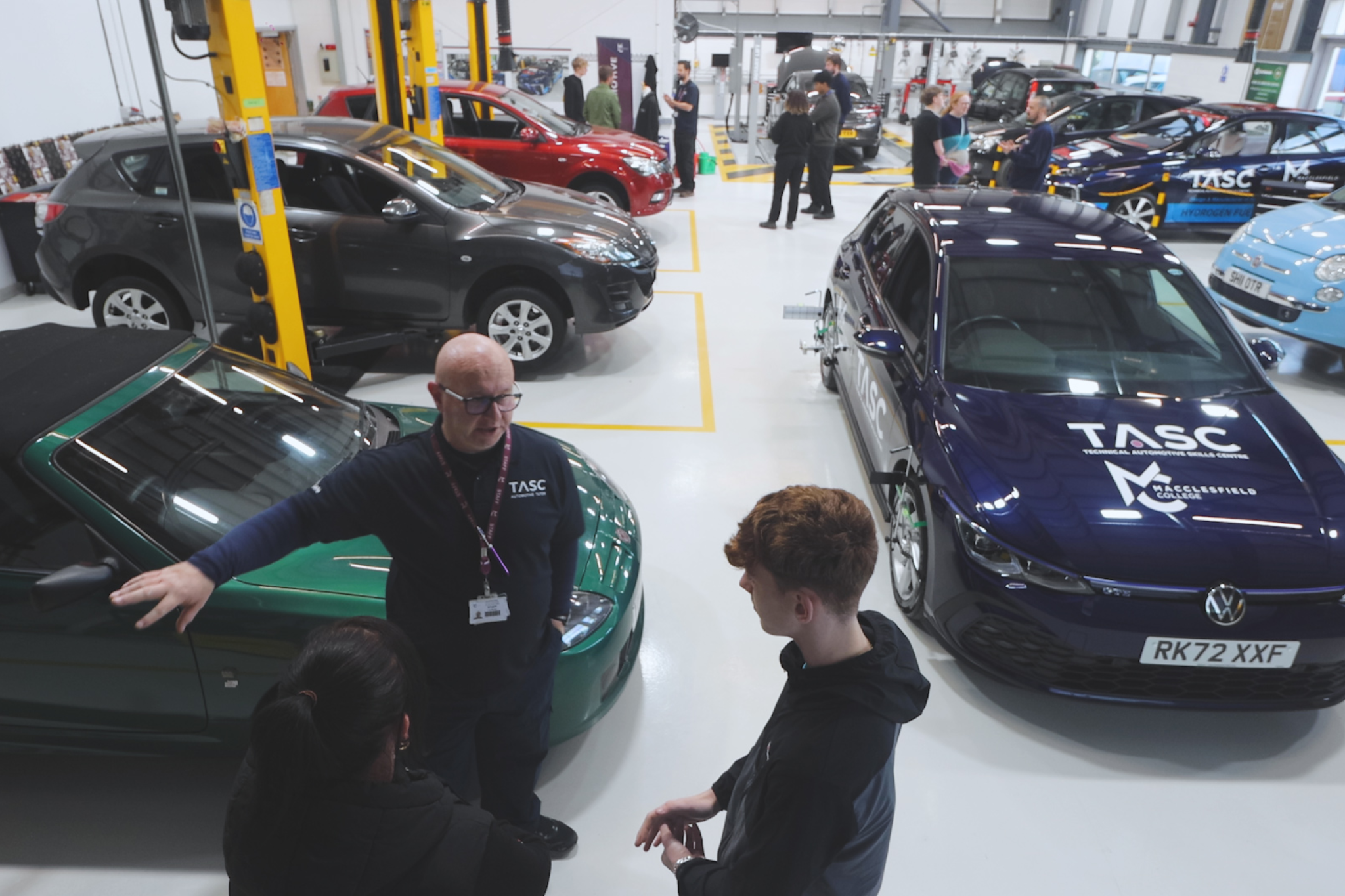 An Automotive teachers talking to families during an Open Event inside Macclesfield College's Automotive workshop