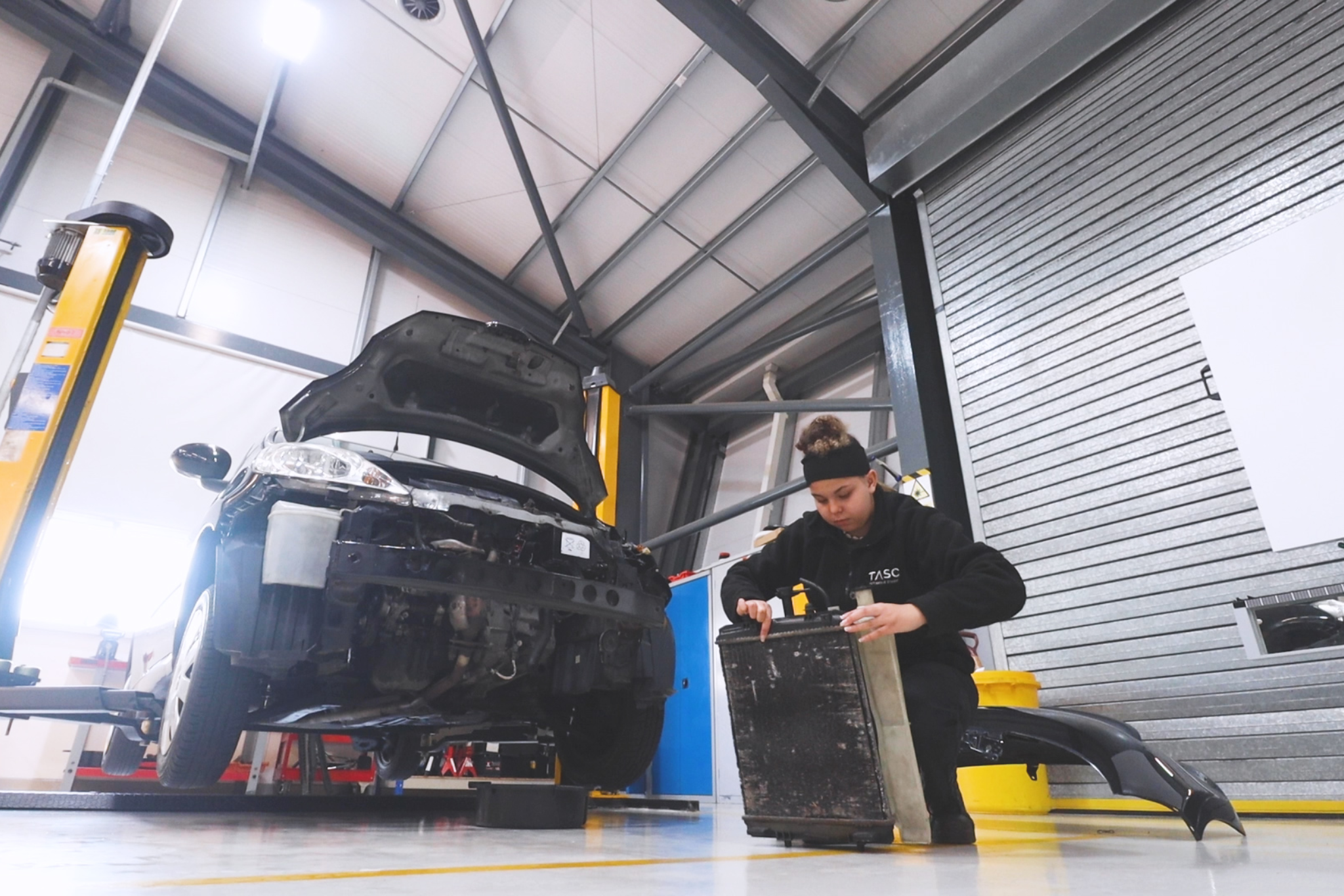 One Automotive student is holding a car radiator