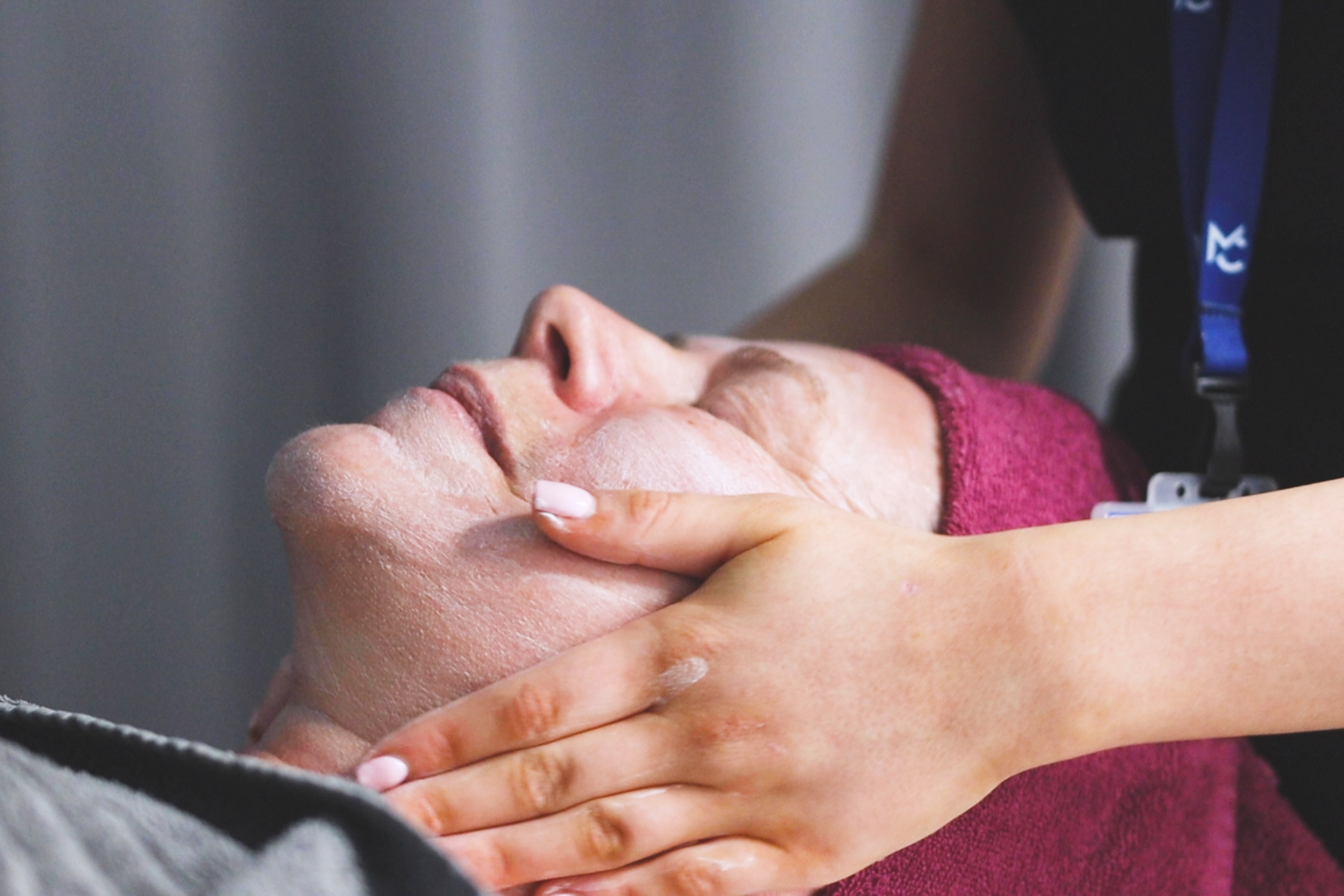 A student is performing a facial massage beauty treatment to a client