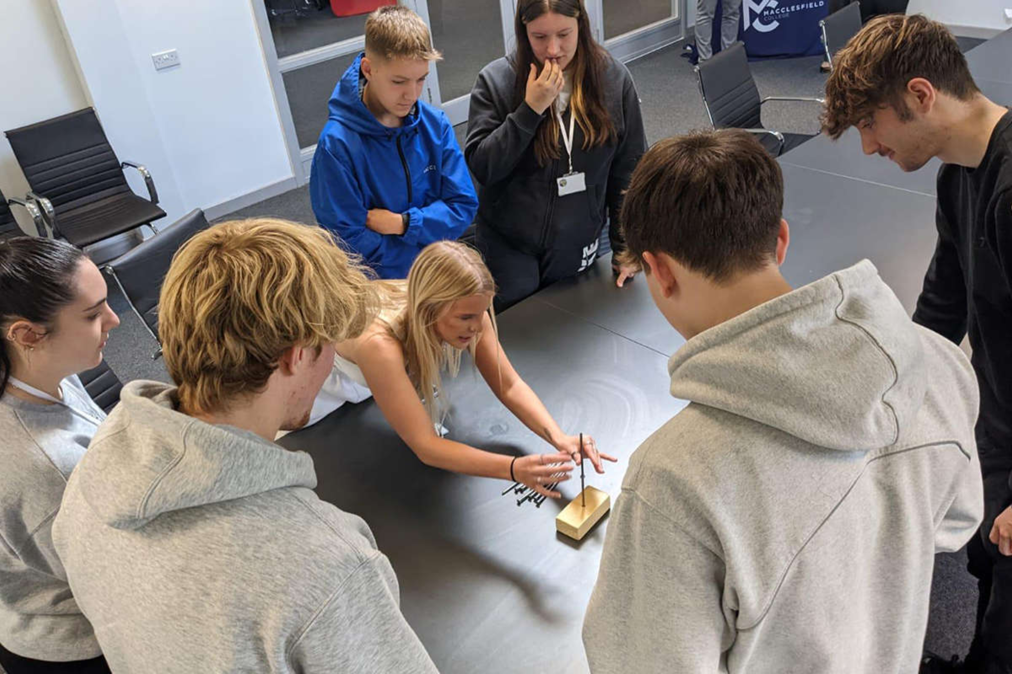 A group of students are stood by a table during a group challenge activity