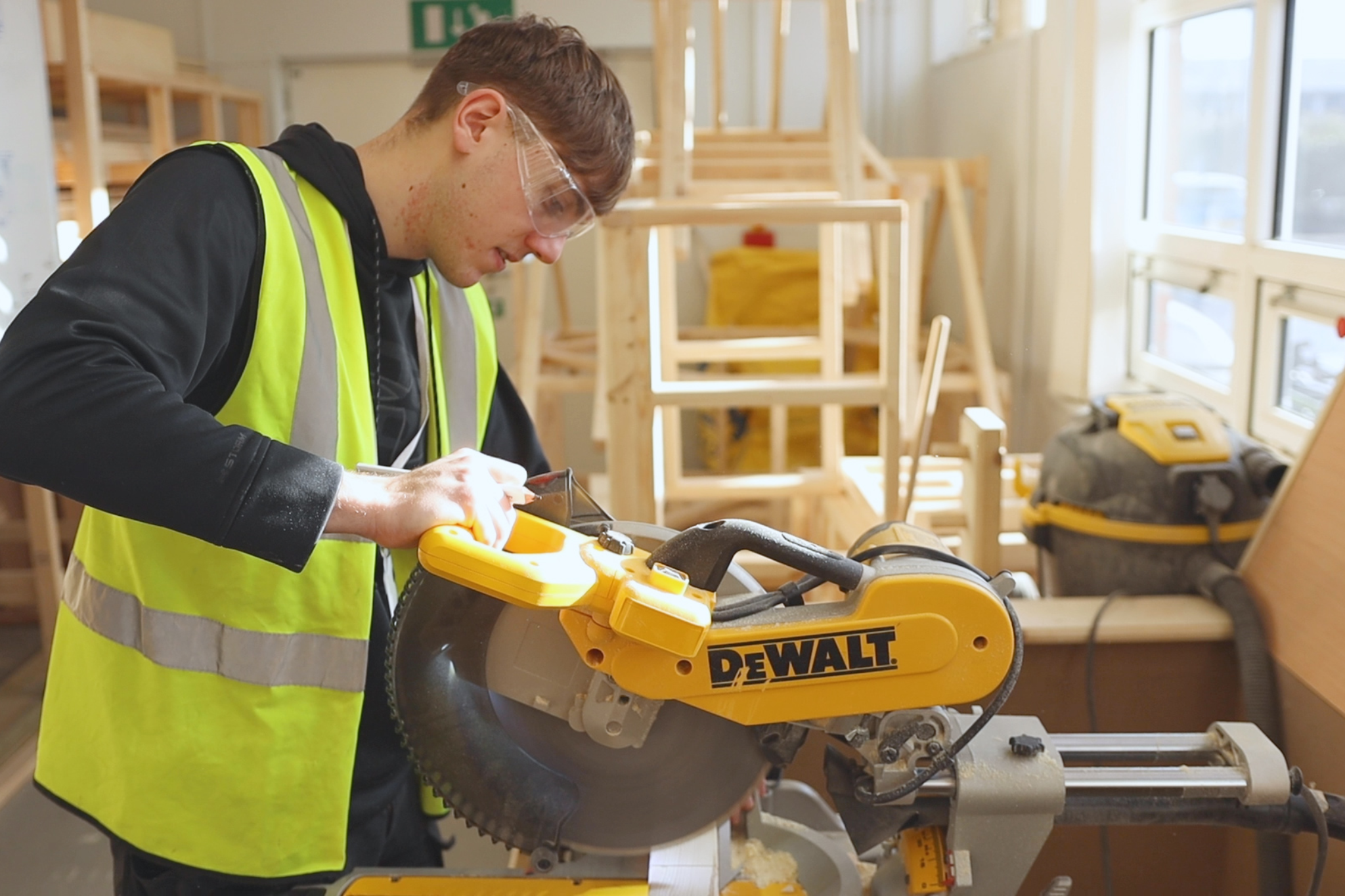 A Carpentry and Joinery apprentice is using a saw machine.
