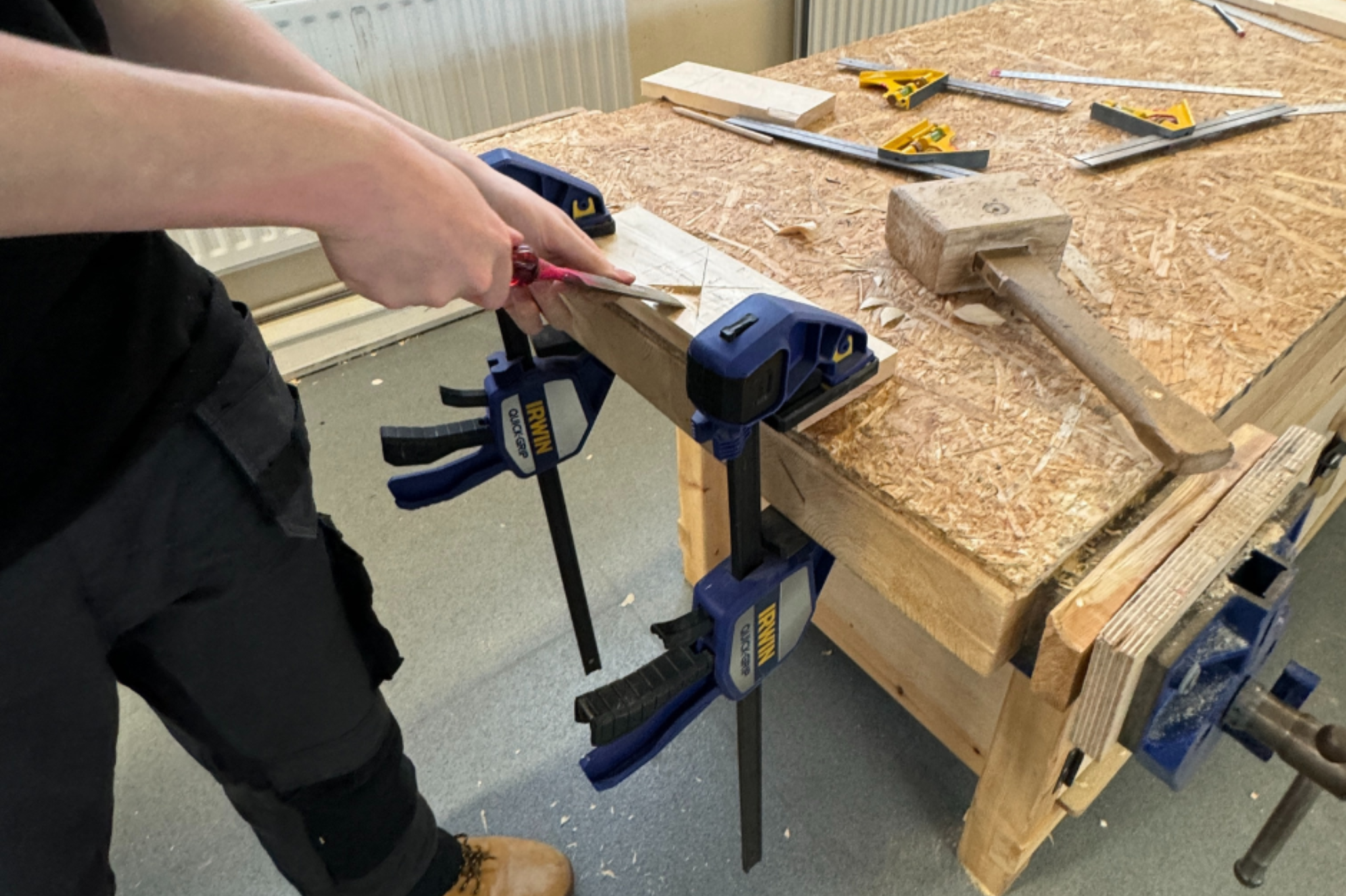 A Carpentry and Joinery student is using tools to carve wood.