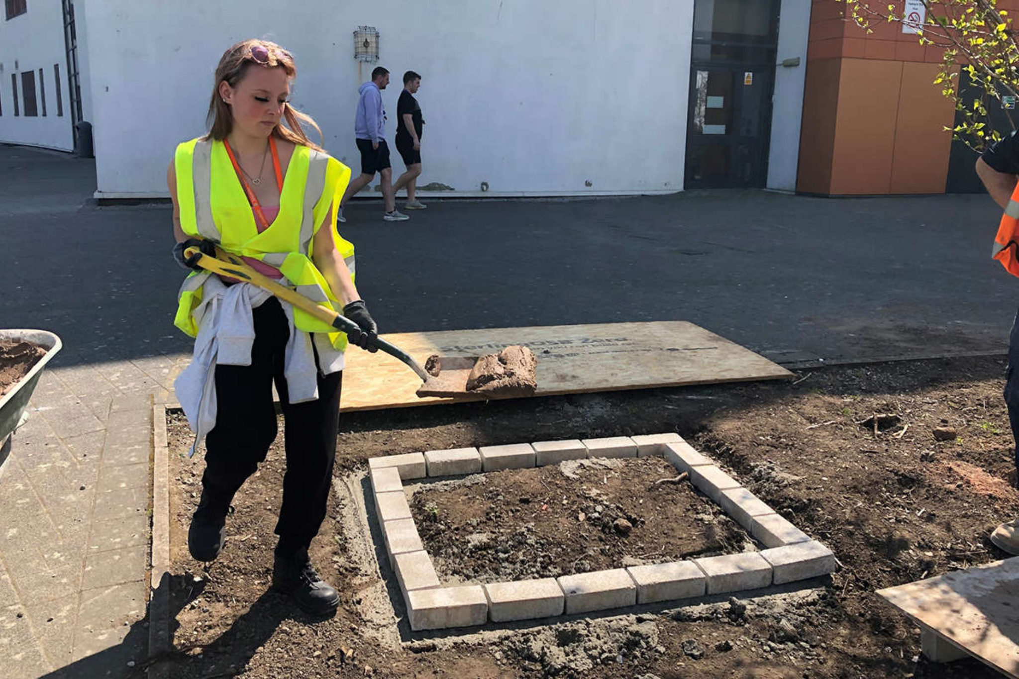 A female construction student is putting cement on a on a partly built wall