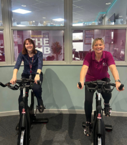 two staff members riding spin bikes
