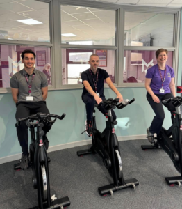 three staff members riding spin bike