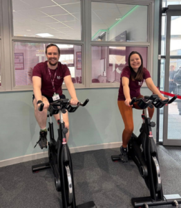 two staff members riding spin bikes