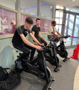three students riding a spin bike