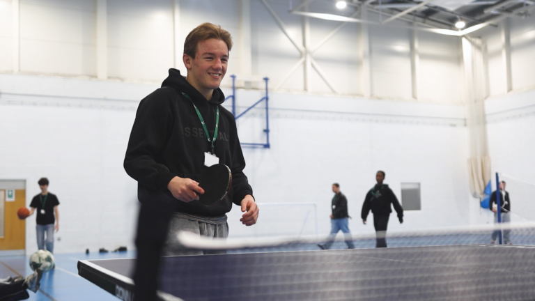 a male student is playing table tennis in a sports hall