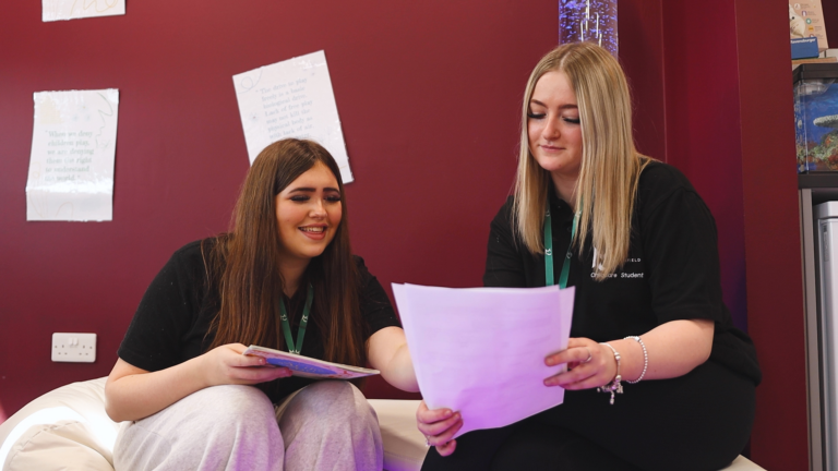 two childcare students are reading a piece of paper