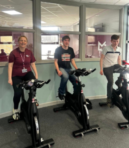 a staff member and two students riding spin bikes
