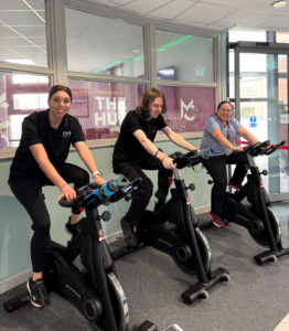 two staff members and a student riding spin bikes