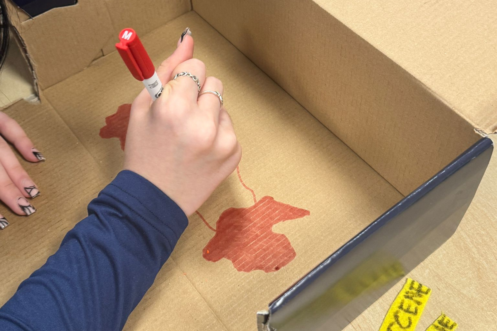 A student is drawing in a shoe box