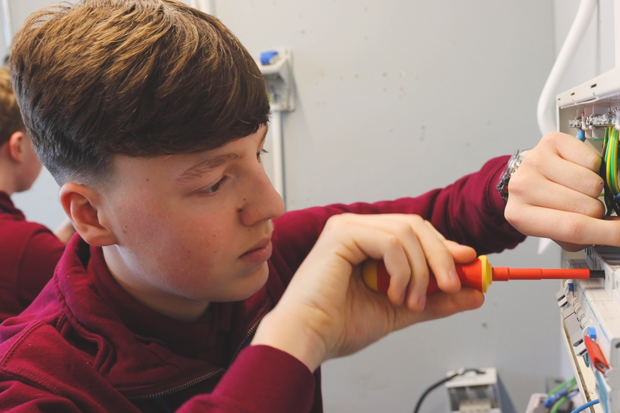 An electrical student is working on a fuse box.