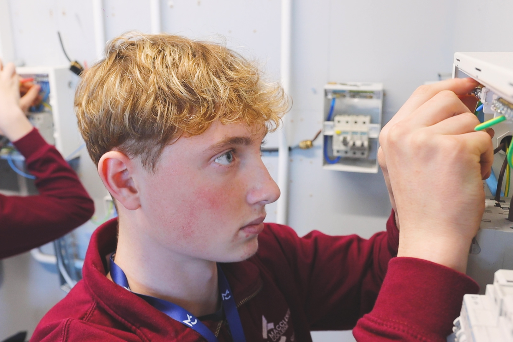 Two electrical students are looking at fuse boxes.