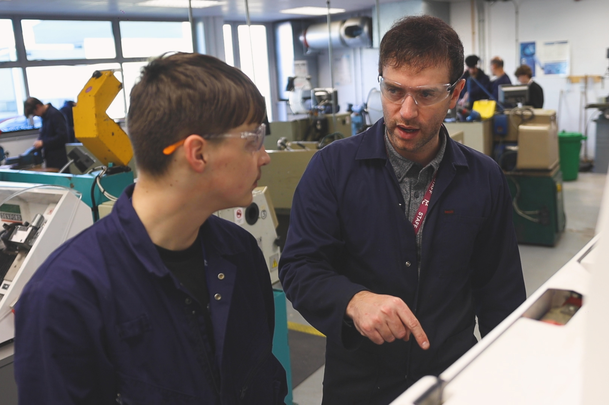 An Engineering student is listening to an Engineering teacher talk about machinery.