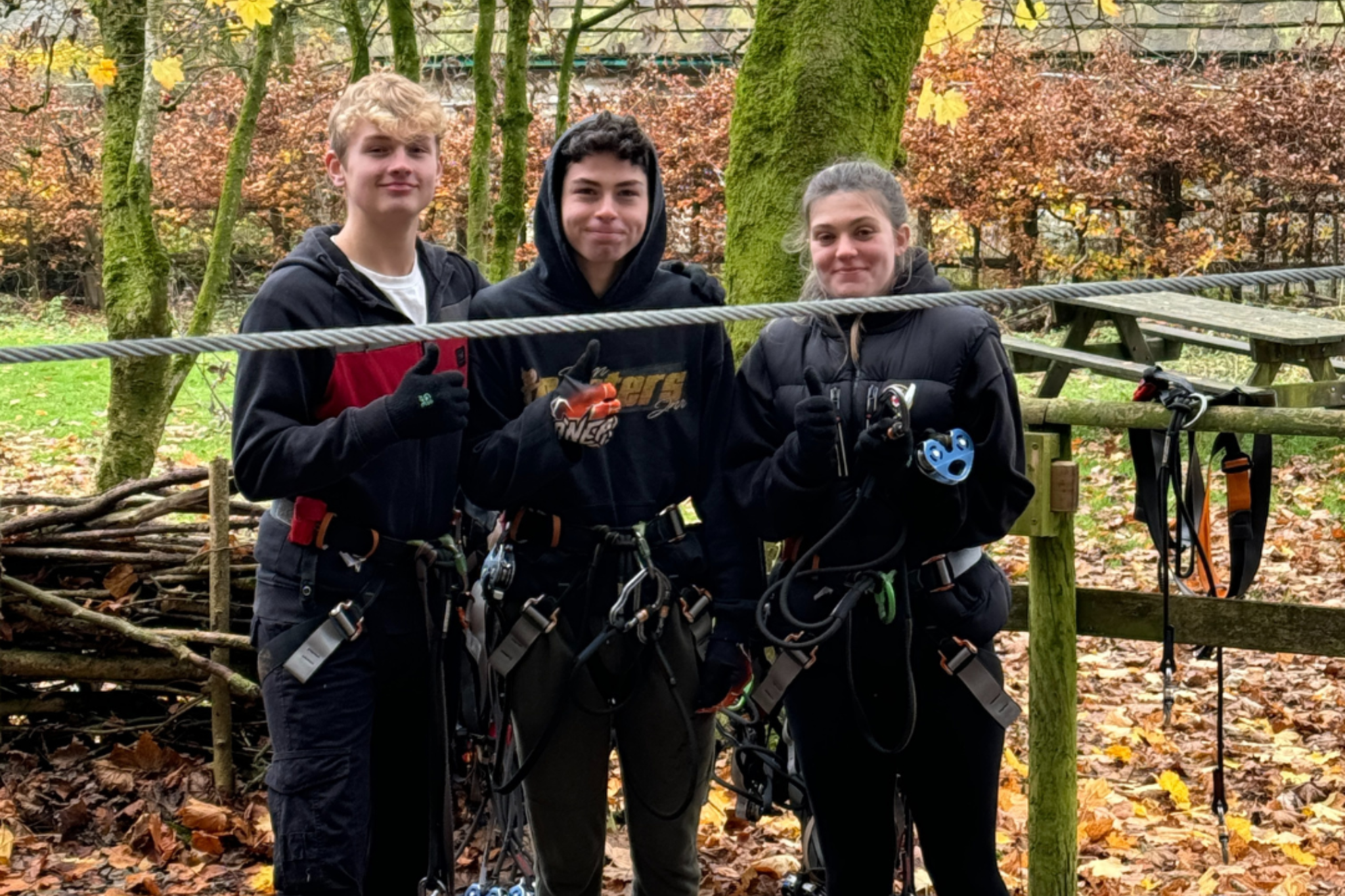 Three students are smiling for a photo during an enrichment trip to Go Ape