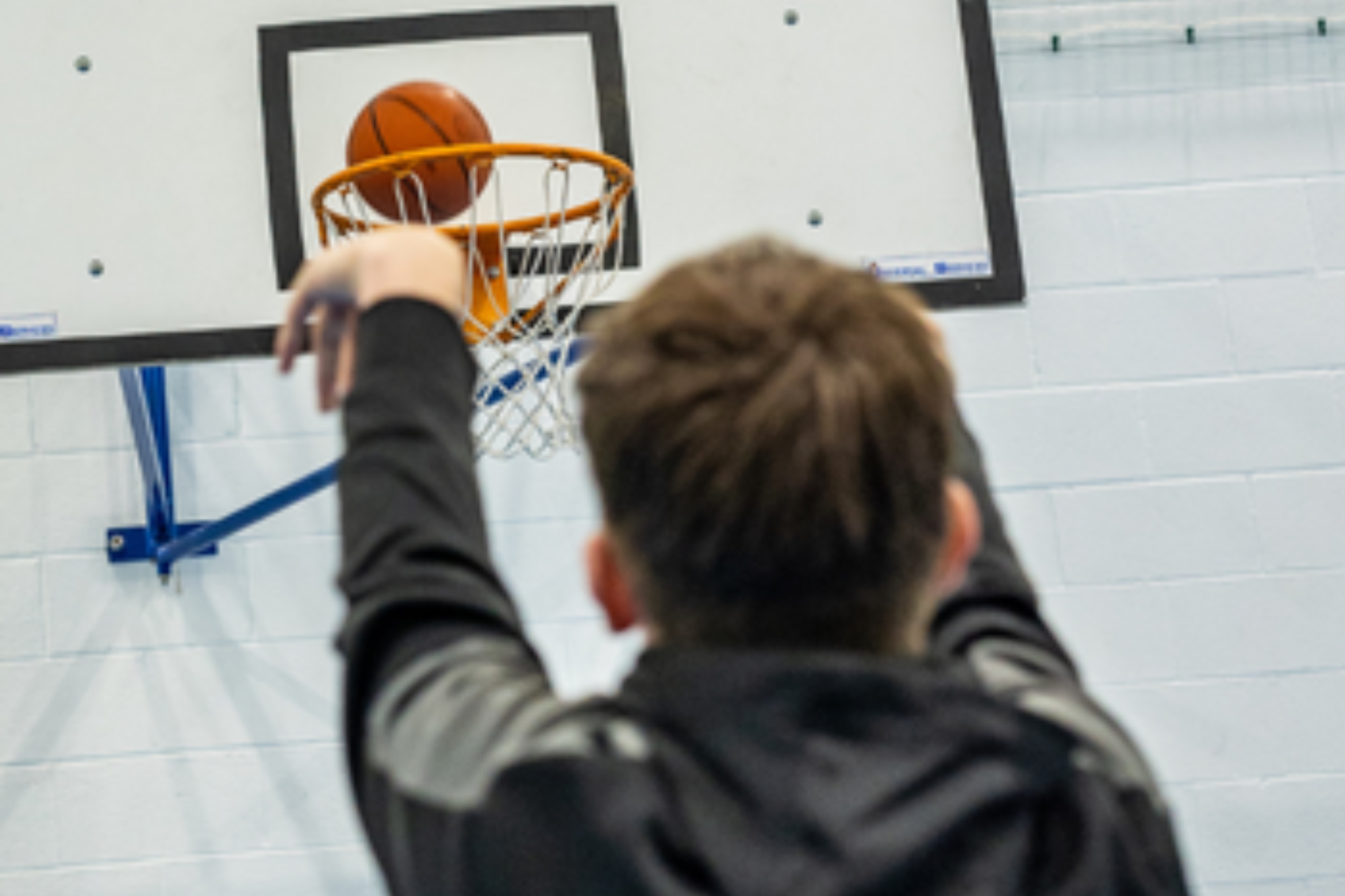 A student is shooting a basketball into a hoop