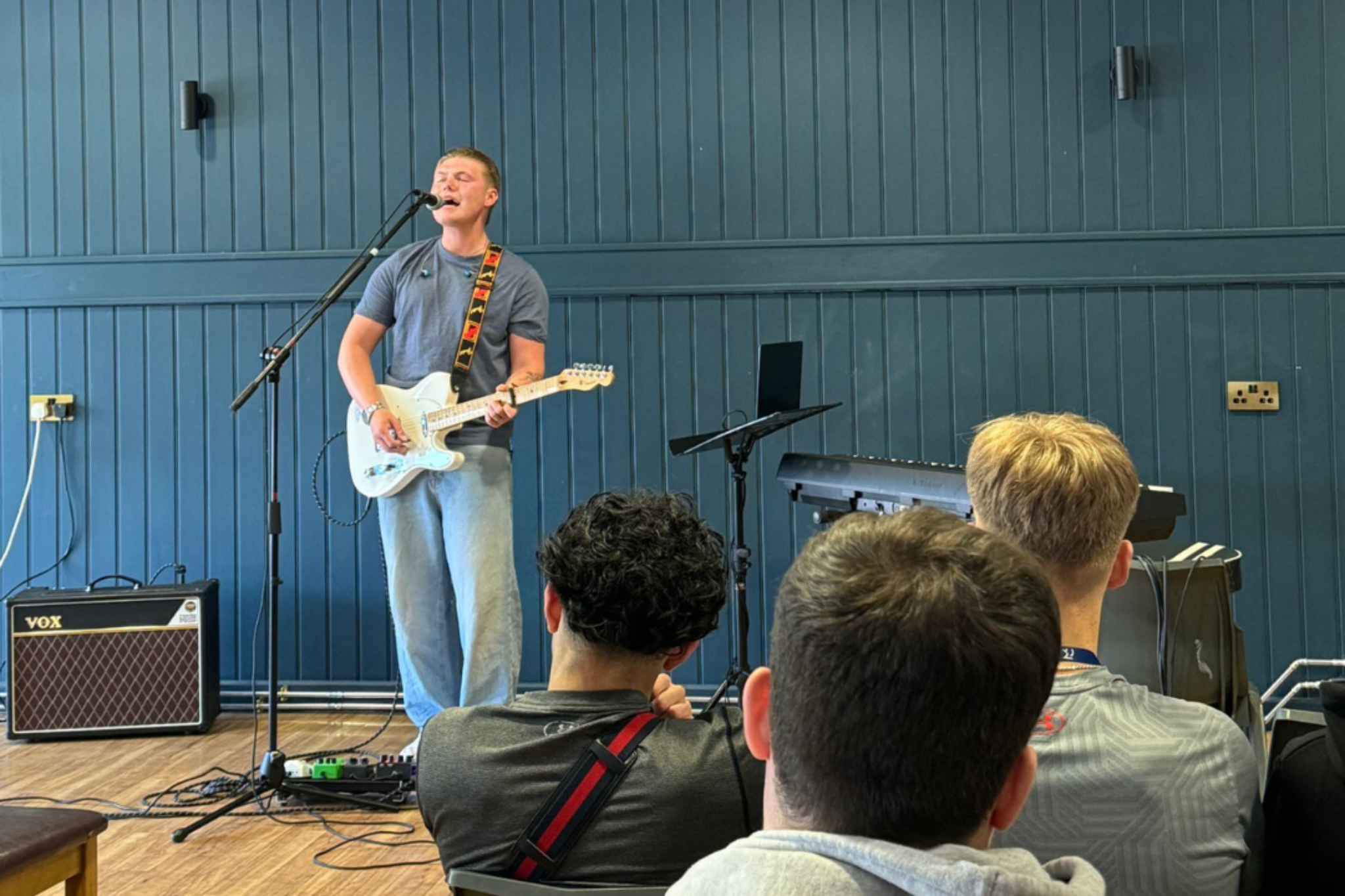A singer is performing and playing the guitar at Macclesfield College