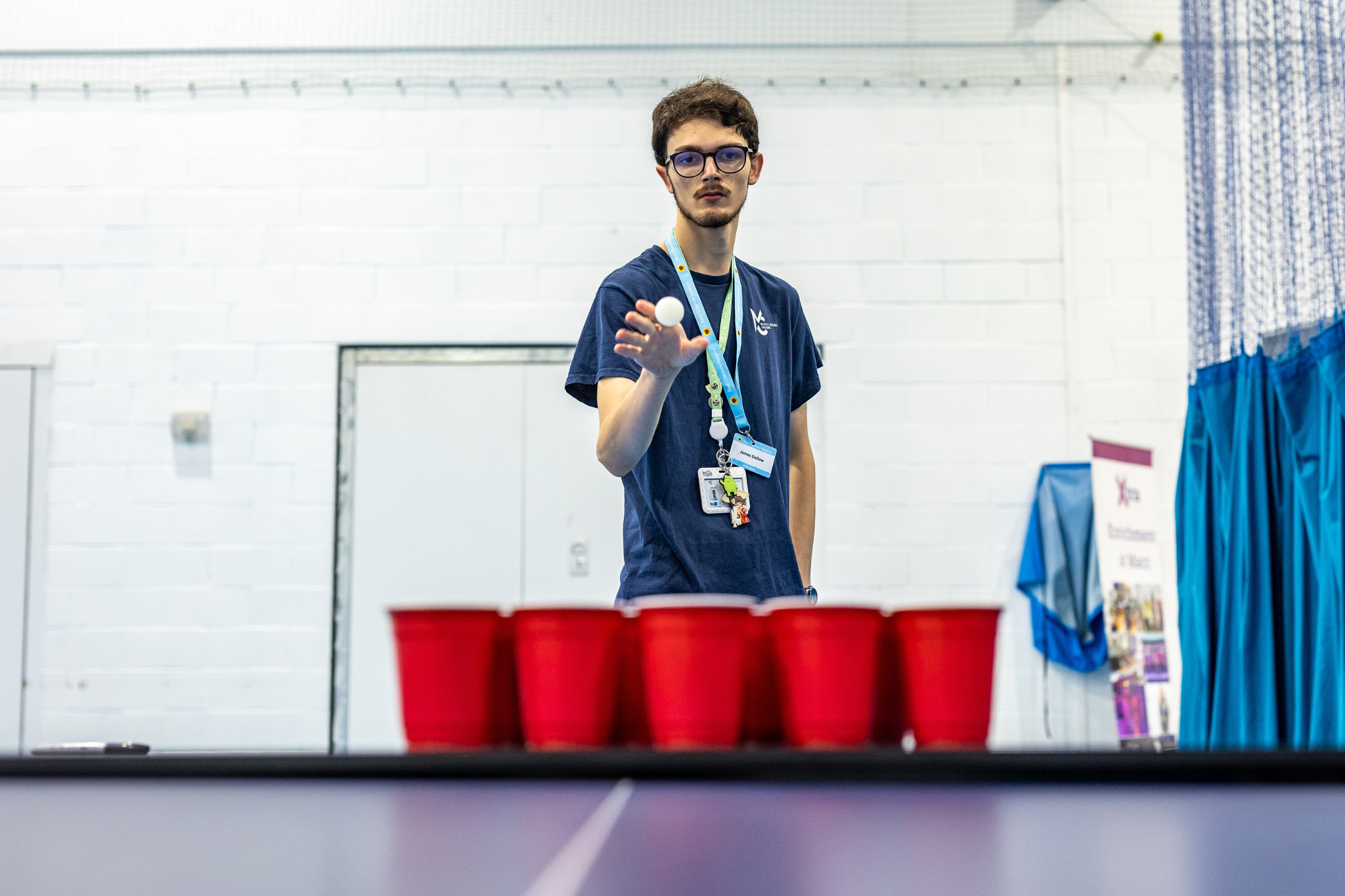 A student is throwing a ping pong ball into red cups