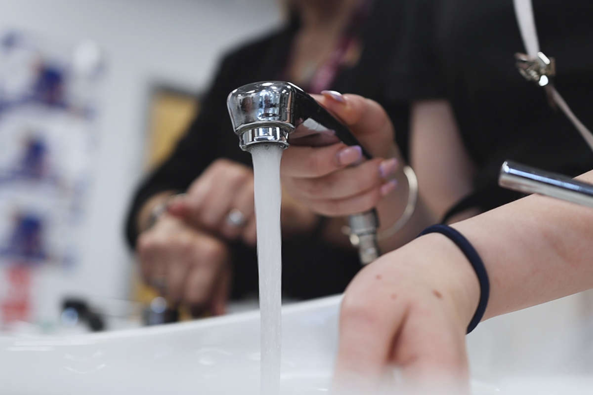 A hairdressing student is running water from a salon tap head