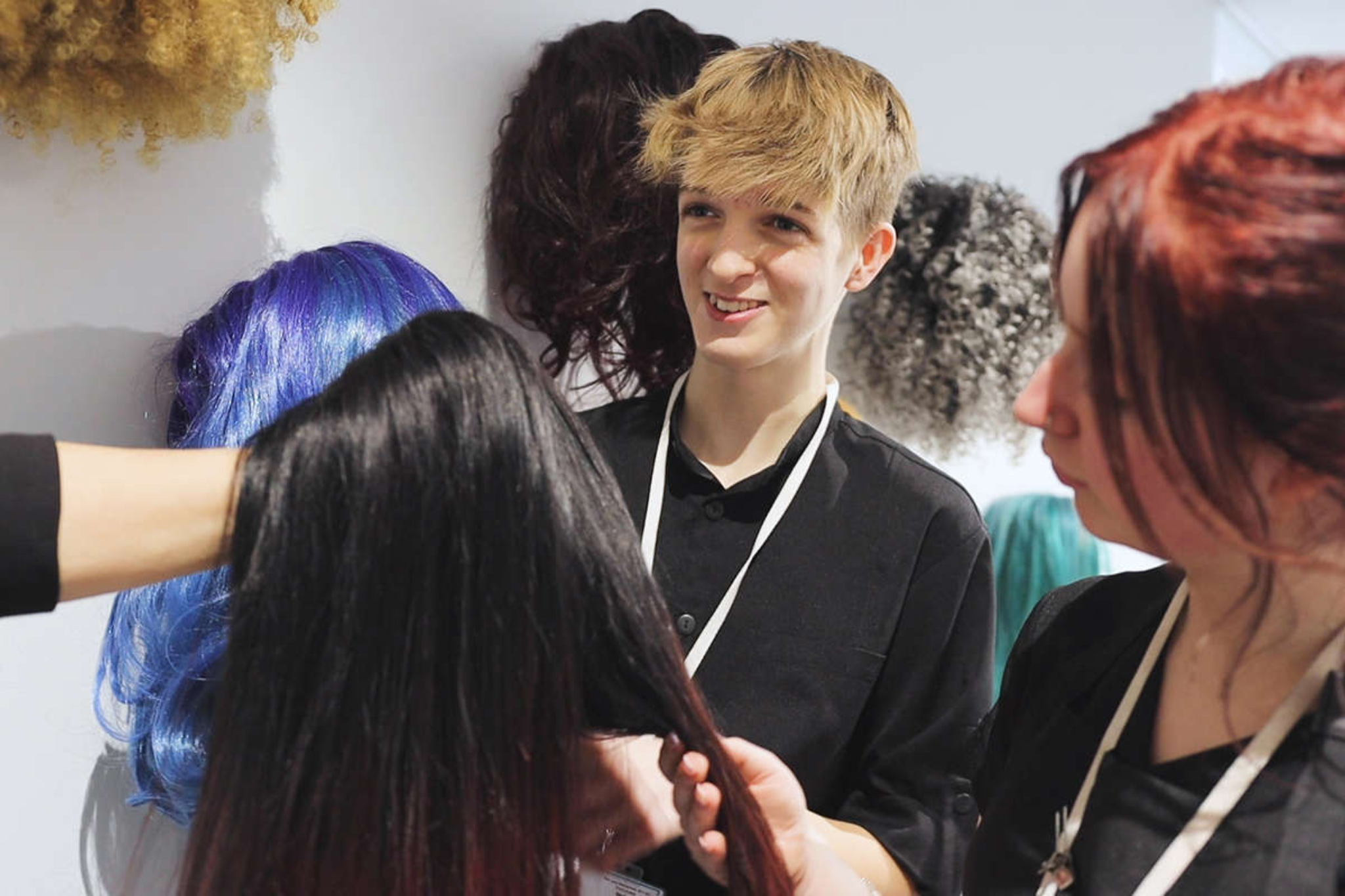 Two hairdressing students are practicing hairstyles on wigs