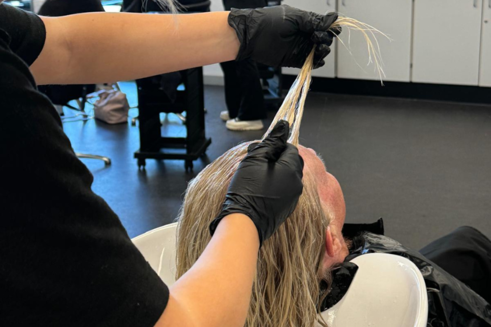 A hairdressing student washing a client's hair.