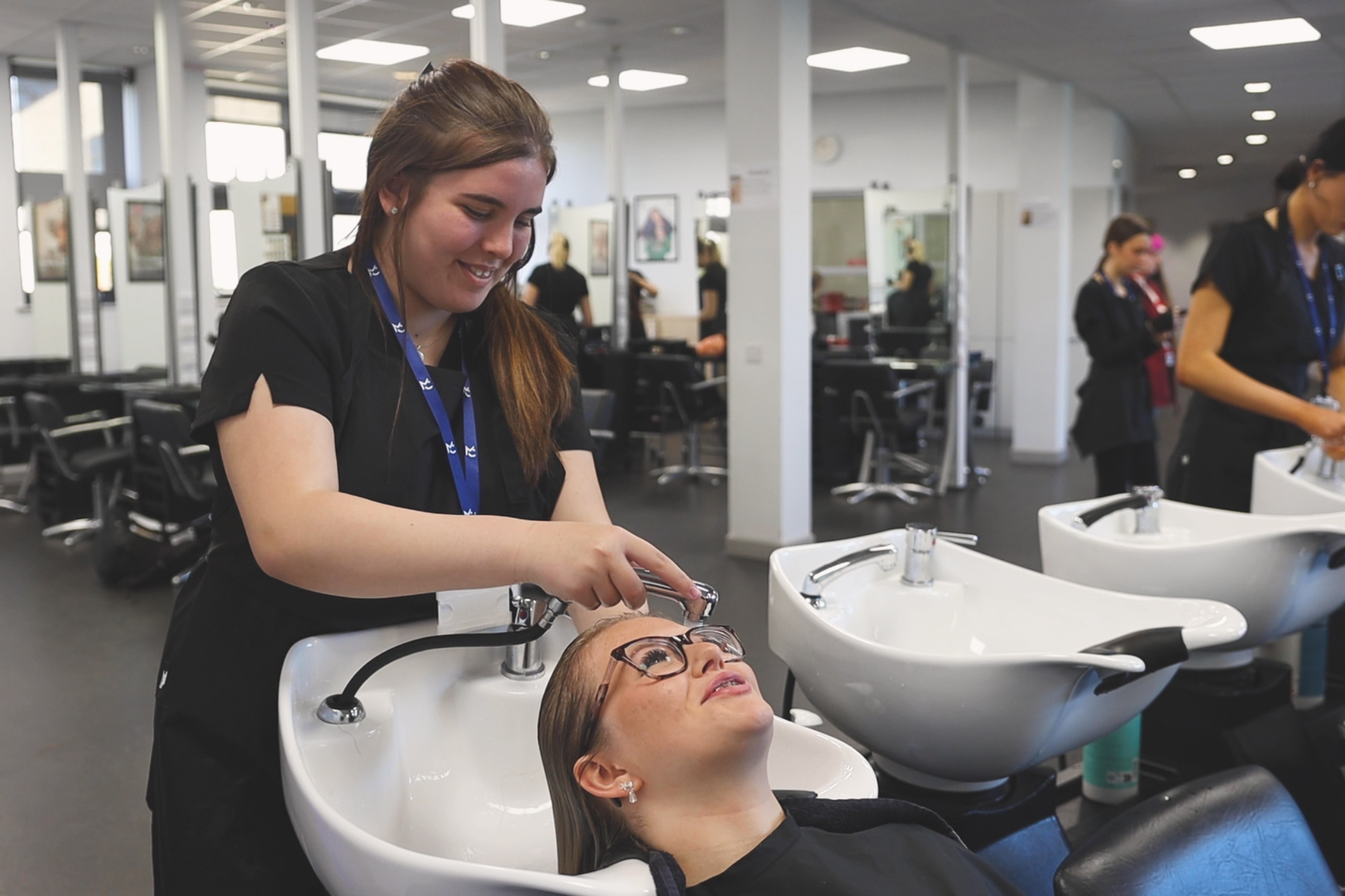 A hairdressing student is washing a client's hair.