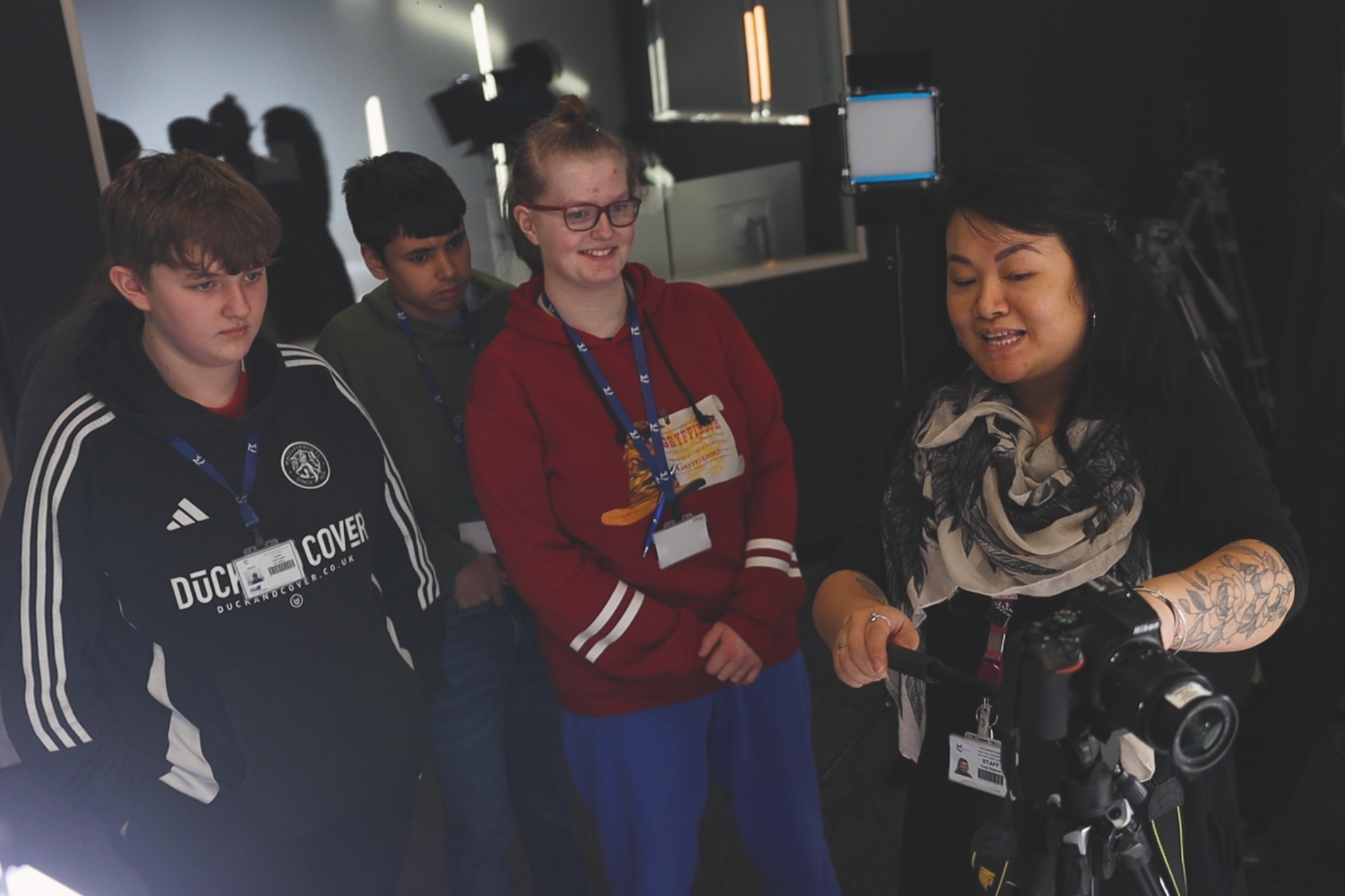 A creative media teacher is showing students about camera equipment.