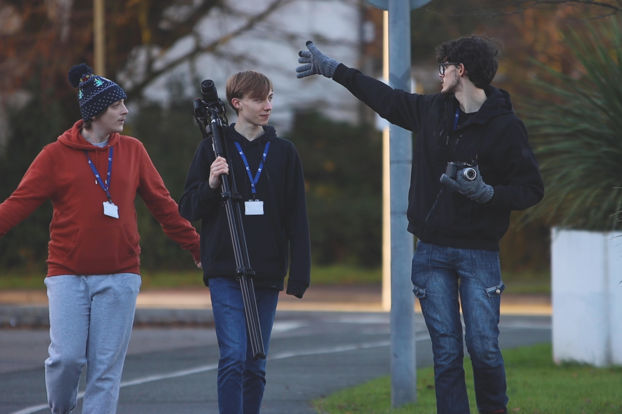 Three Creative Media students are walking while carrying camera equipment.