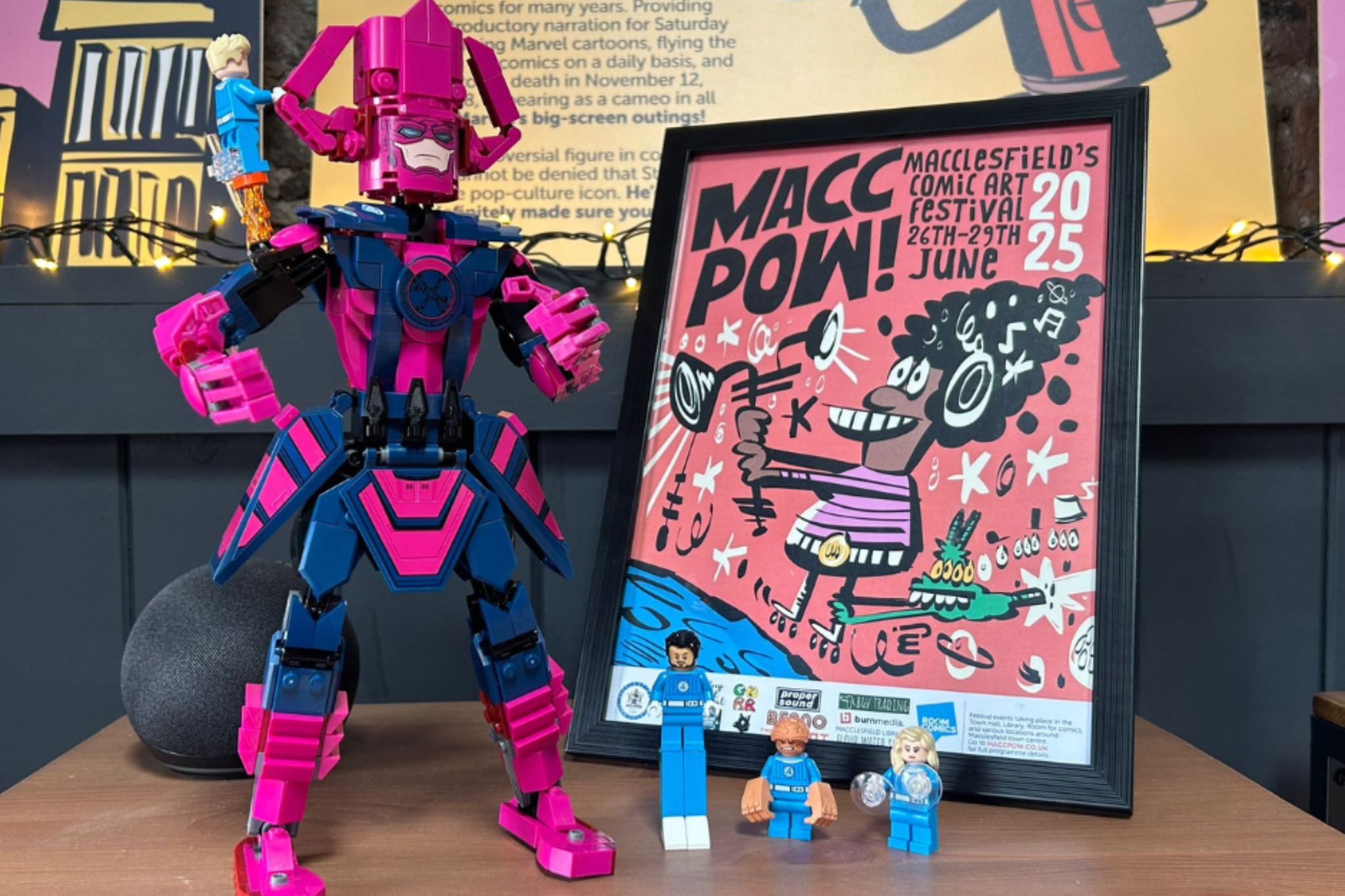 A Macc Pow poster in the black frame. Next to the poster is some Lego figures.