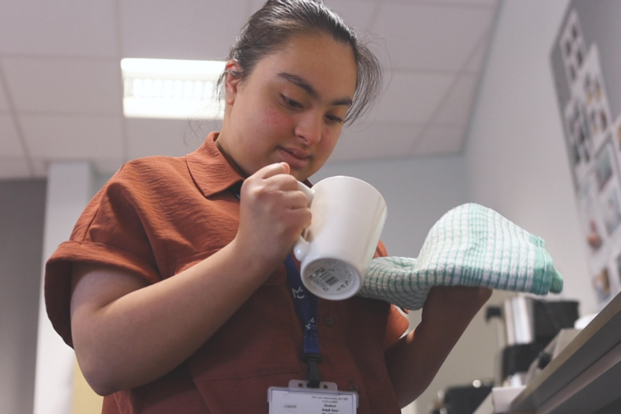 A Pathways student is washing a mug.