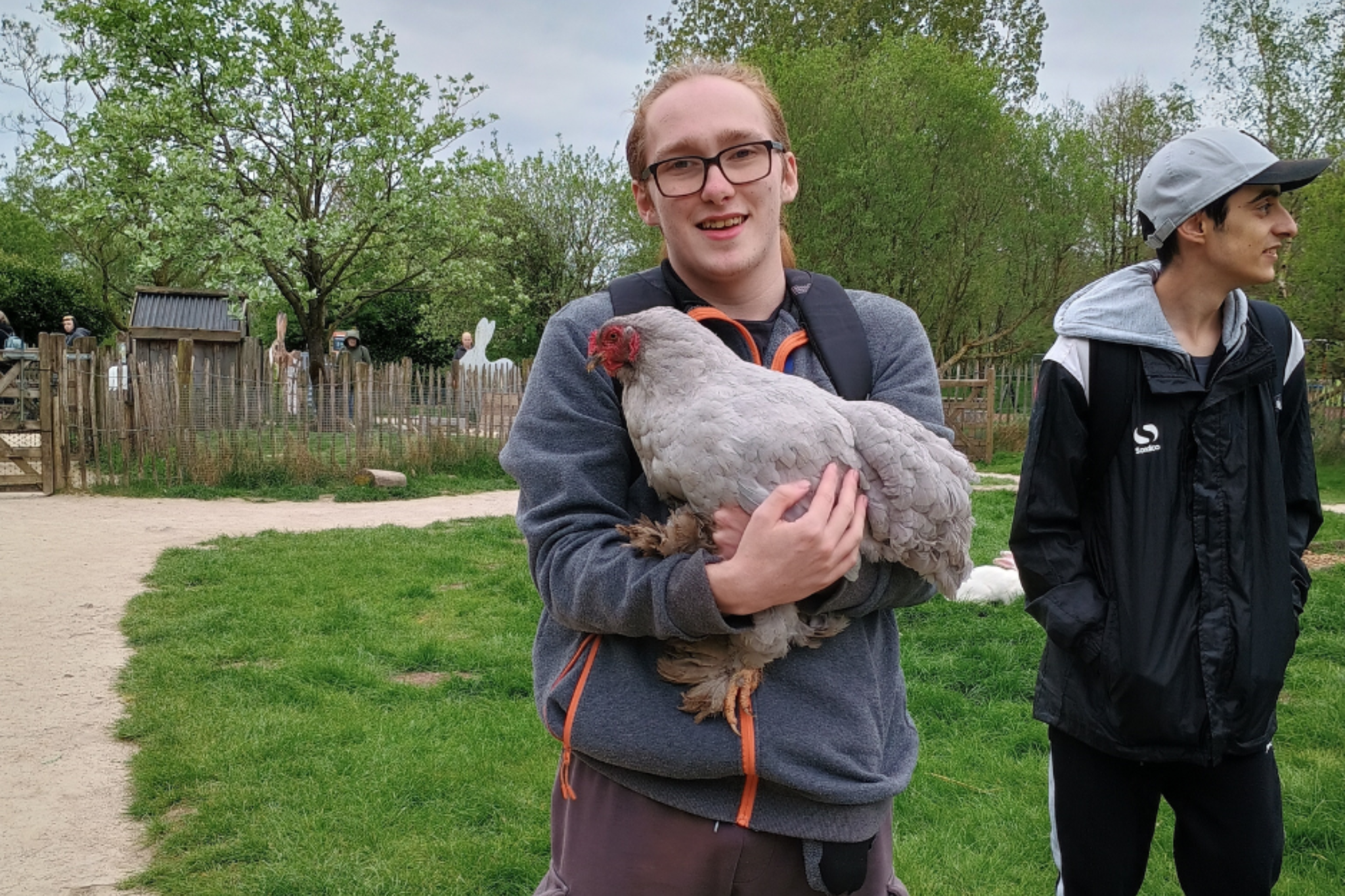 A Pathways student is holding a chicken, during a trip to Peak Wildlife Zoo.