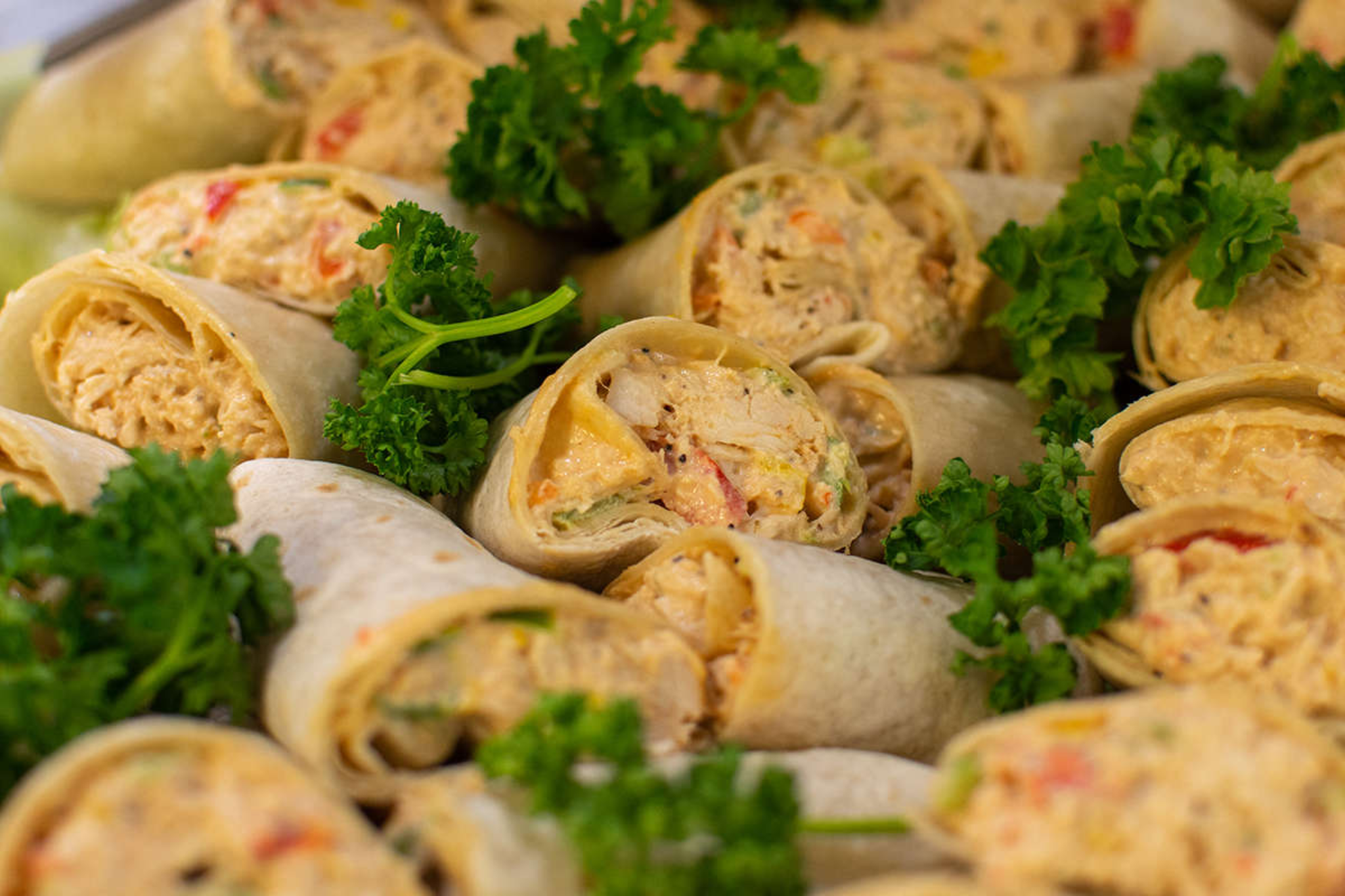 The image shows a close up shot of a tray filled with chicken wraps.