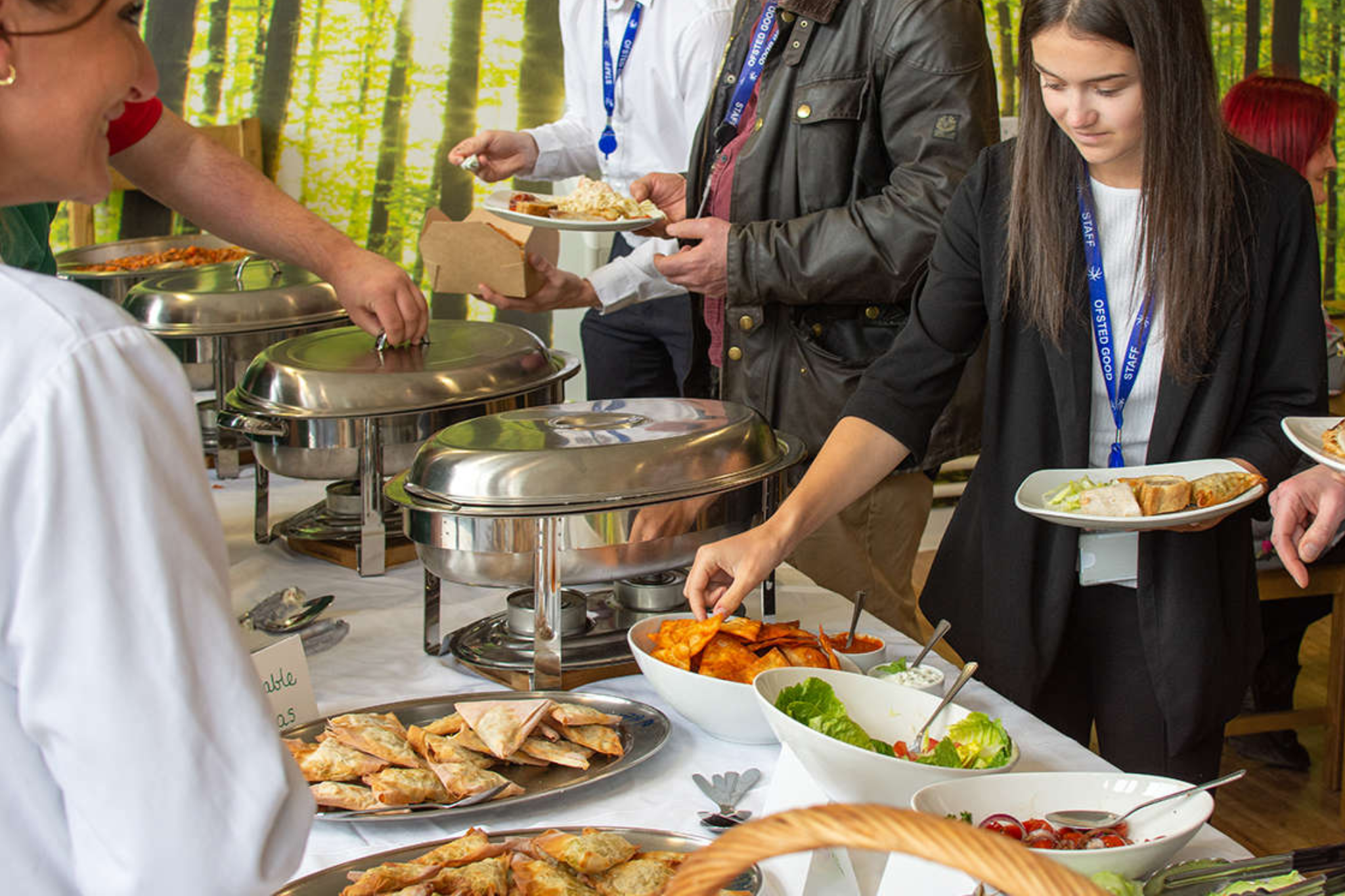 A staff member is helping herself to food from a buffet table.