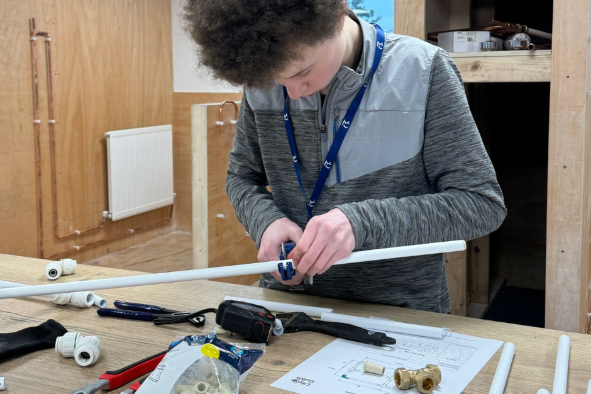 A Plumbing student is cutting plastic pipes.