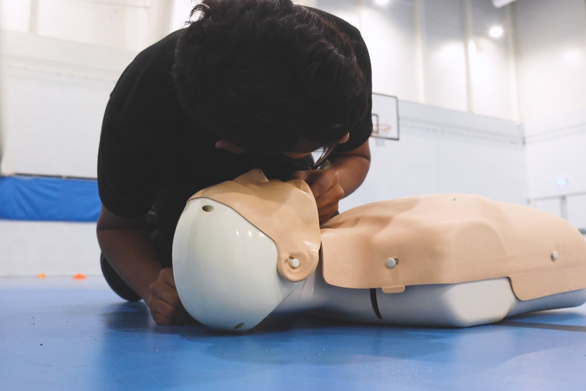 A Public Service student is performing CPR on a CPR dummy.
