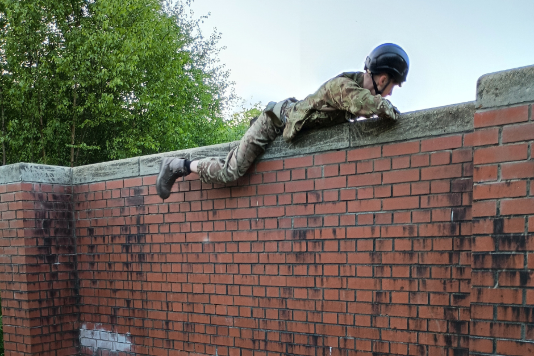 A Public Service student is climbing a wall during an army camp trip.