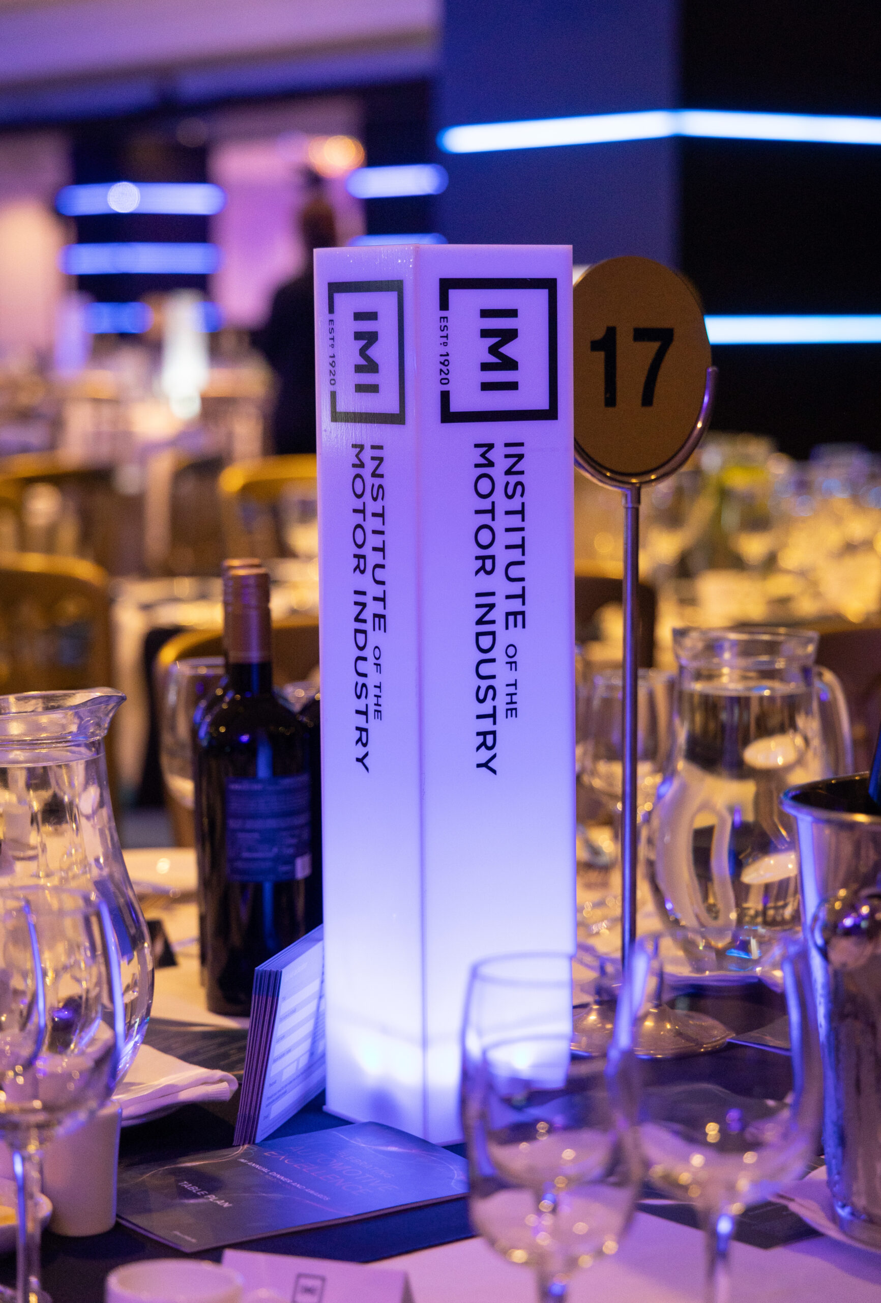 A white award that reads IMI Institute of the Motor Industry sits on a table filled with wine glasses
