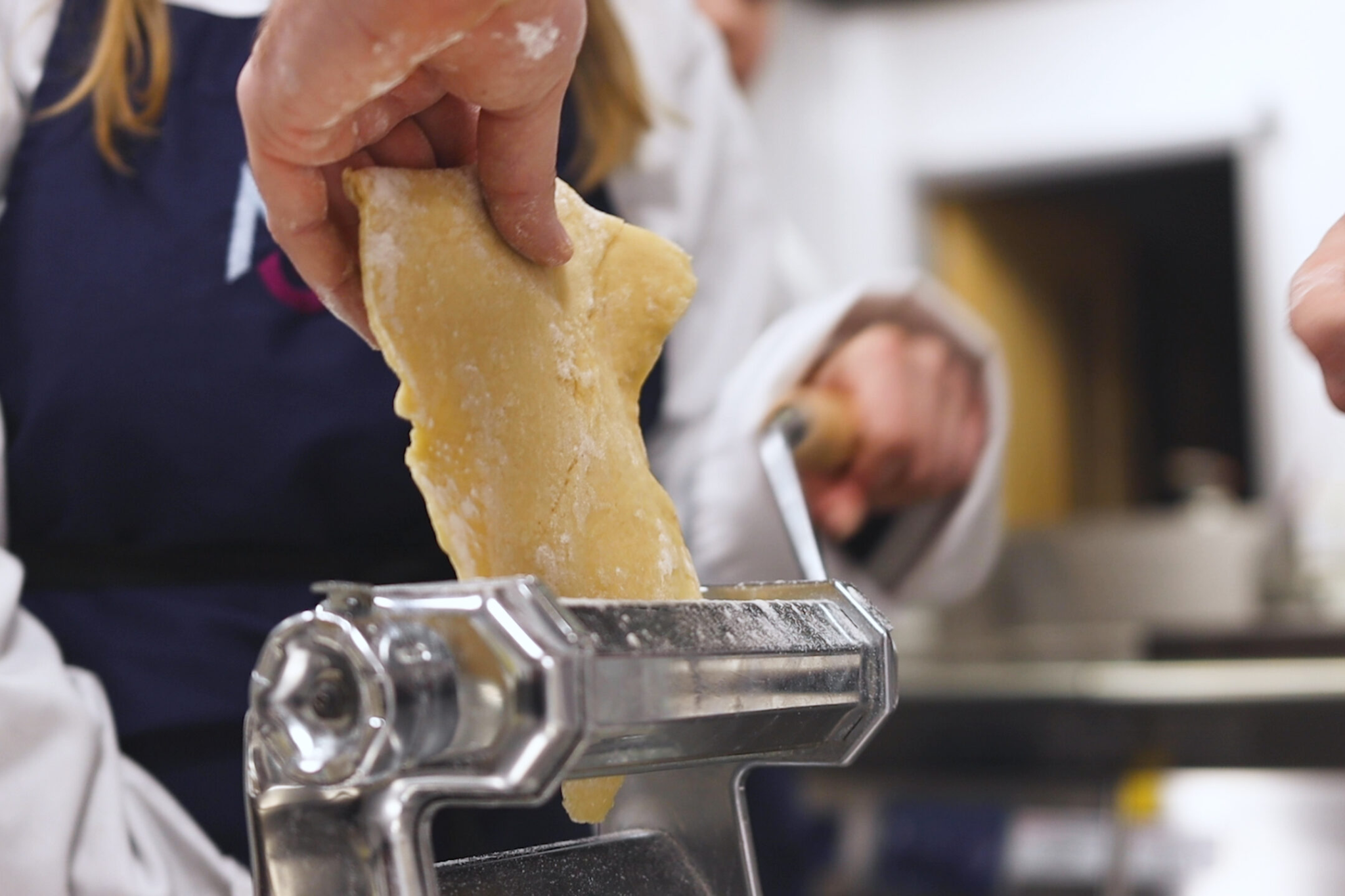 A Whites Chef Academy teacher is making pasta with a pasta machine.