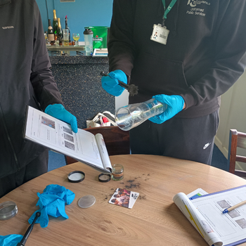 two public service students are dusting object during a crime investigation activity