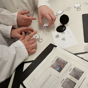 a group of students wearing lab coats making finger printing