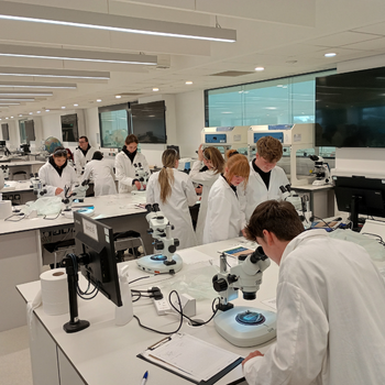 a group of students are wearing lab coats whilst working in a lab