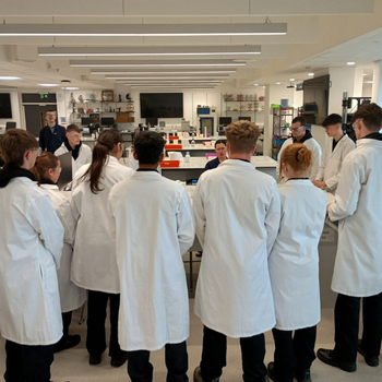 a group of students wearing lab coats are standing around a table