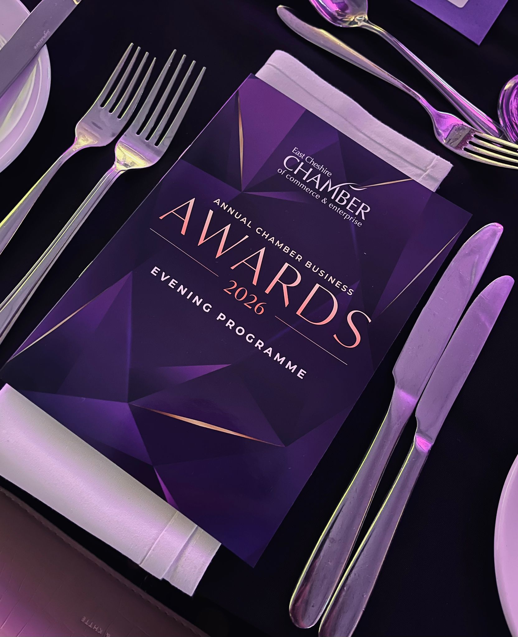 a table is set with cutlery and a flyer that reads annual chamber business awards 2026 evening programme