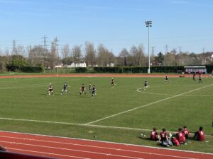 a group of students are playing football on a football pitch on a sunny day