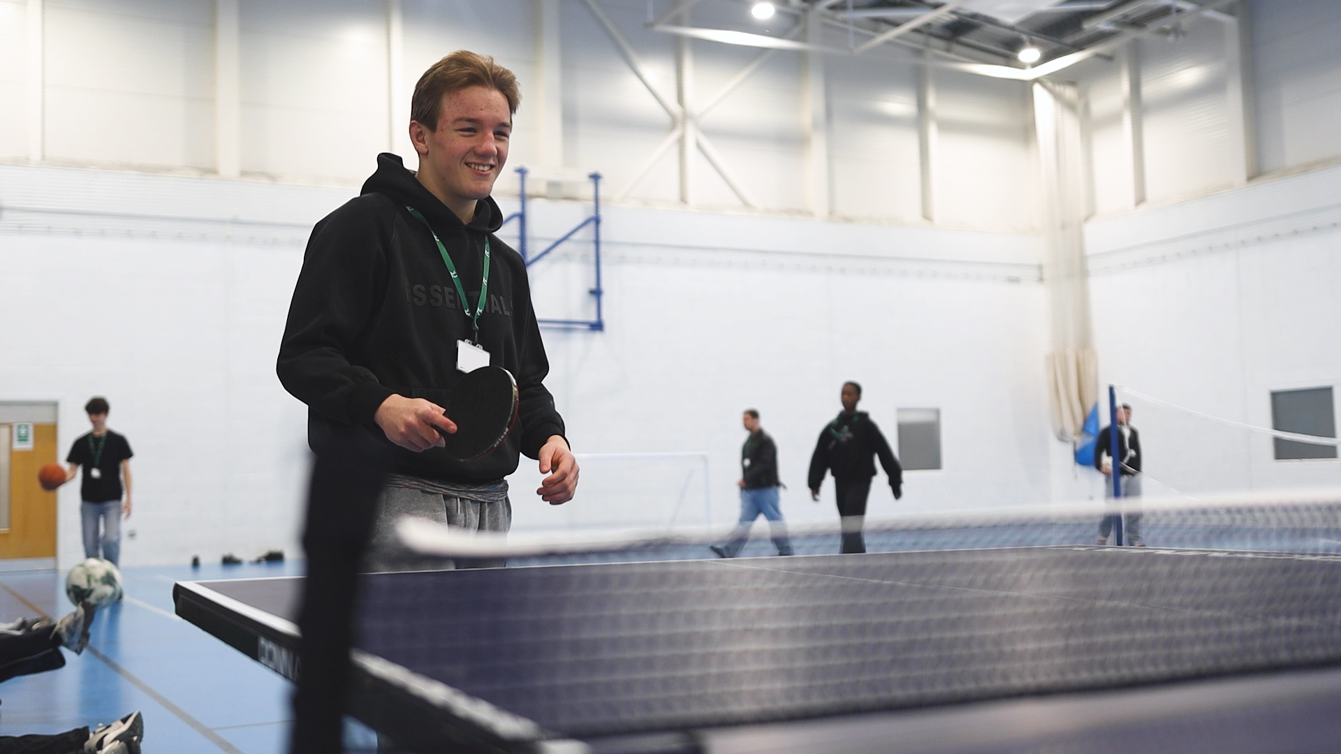 a student playing table tennis inside a sports hall